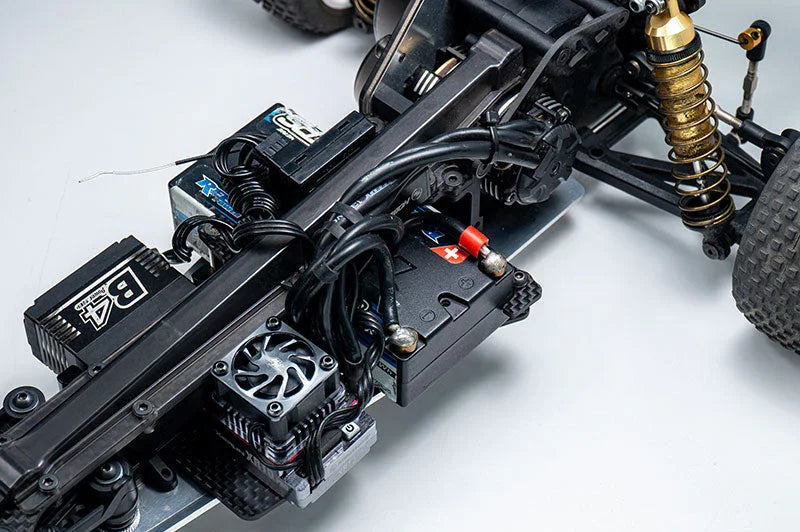 Close-up of RC car chassis showing electronics, battery, wiring, and shock absorber