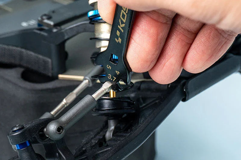 Hand using RC car turnbuckle wrench tool to adjust suspension component