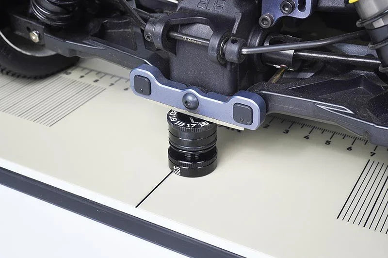 RC car setup station with ride height gauge measuring chassis on marked board