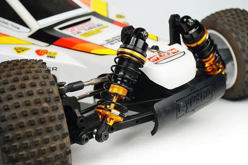 Close-up of RC car front suspension with shock absorbers, off-road tires, and detailed chassis.