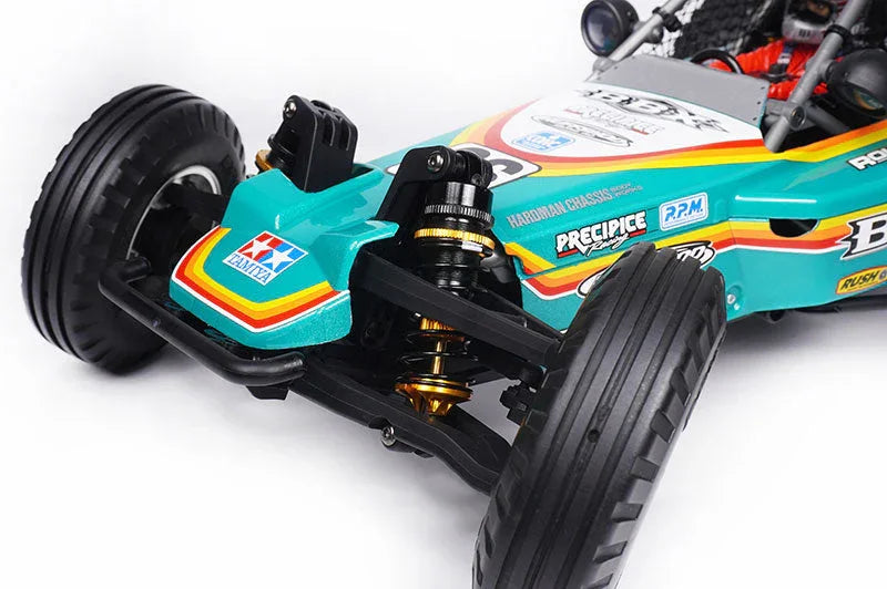 Close-up of a teal RC buggy front suspension, durable off-road tires, and racing decals