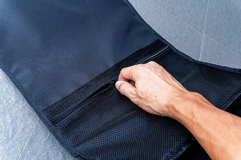 Hand opening a black mesh zippered pocket in an RC tool pit bag on a tiled floor