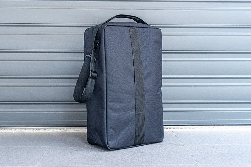 Large black RC pit bag with shoulder strap placed outdoors on concrete in front of a gray garage door.