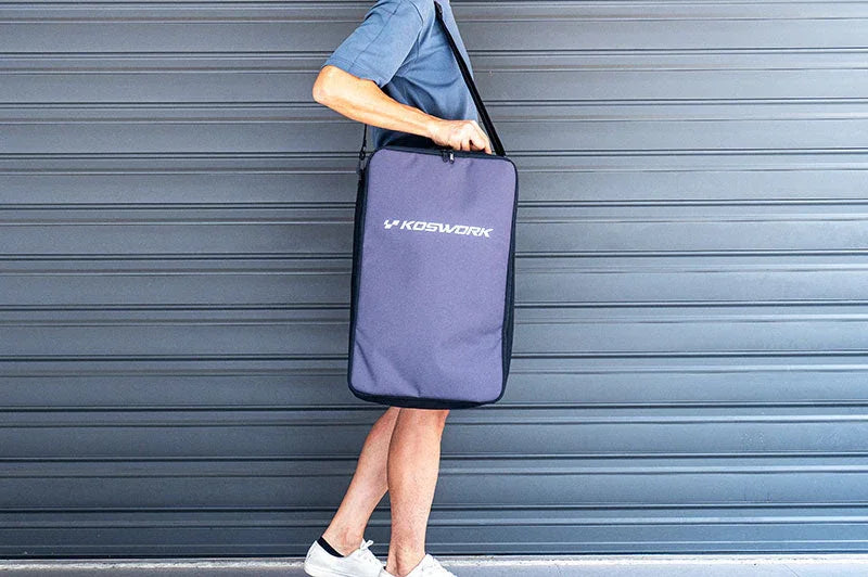 Person carrying a large Koswork RC pit bag with shoulder strap in front of a gray garage door