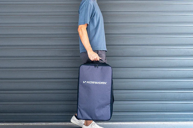 Person carrying large Koswork RC pit bag with handle in front of a grey garage door