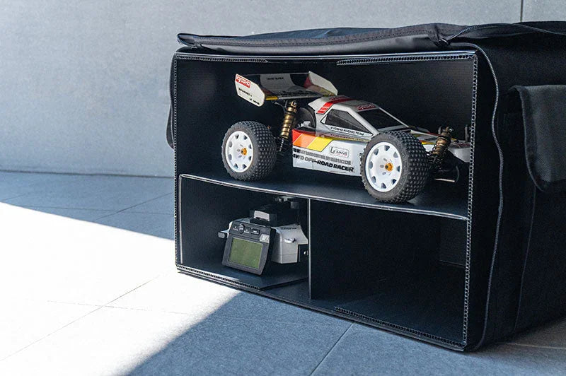 RC car and controller stored in a divided black pit bag on a tiled floor