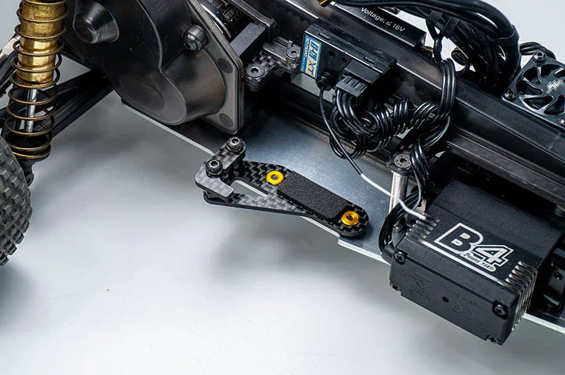 Close-up of an RC car chassis featuring carbon fiber servo mount, electronics, and suspension components.