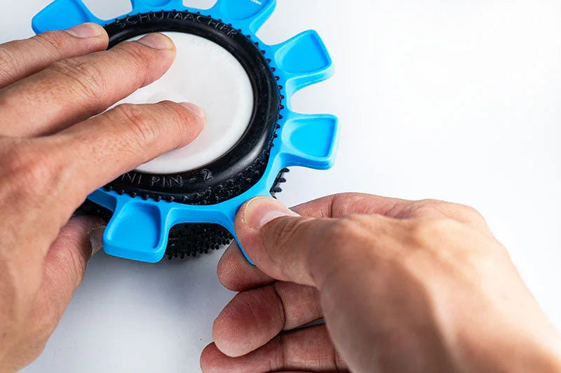 Hands using blue RC tire installation tool on rubber RC car tire