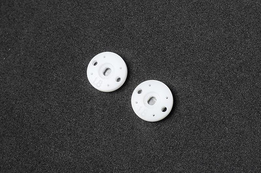 Pair of white RC shock pistons with multiple holes on black foam background