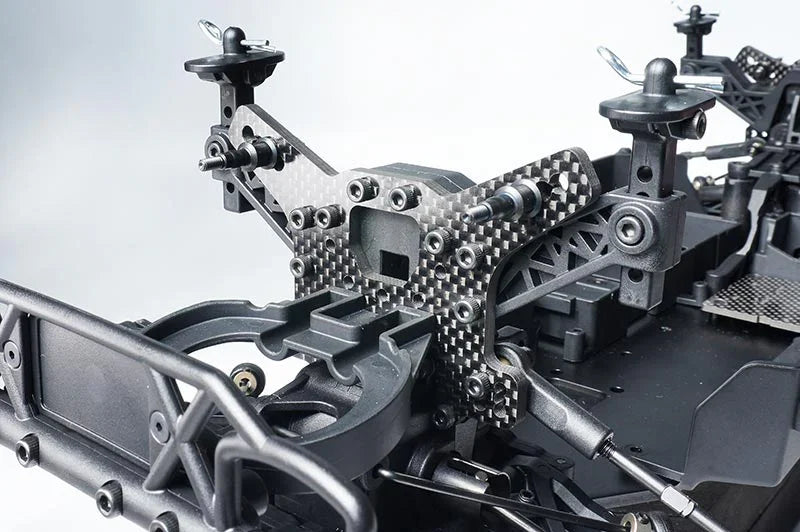 Close-up of carbon fiber RC car chassis with shock towers and detailed suspension parts