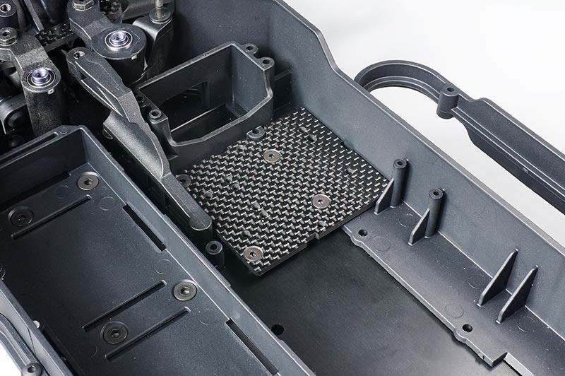 Close-up of RC car chassis with installed carbon fiber battery tray upgrade part