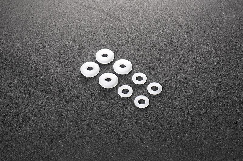 Assorted white nylon RC washers arranged on a dark textured surface