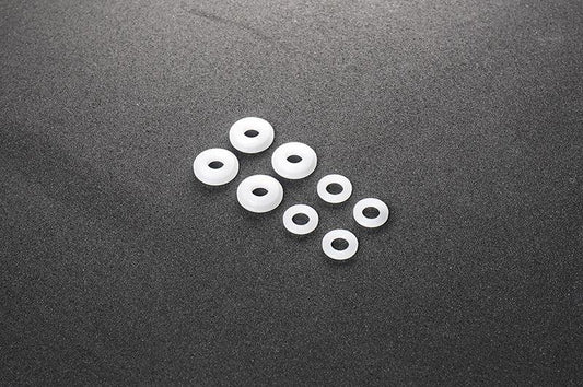 Assorted white nylon RC washers arranged on a dark textured surface