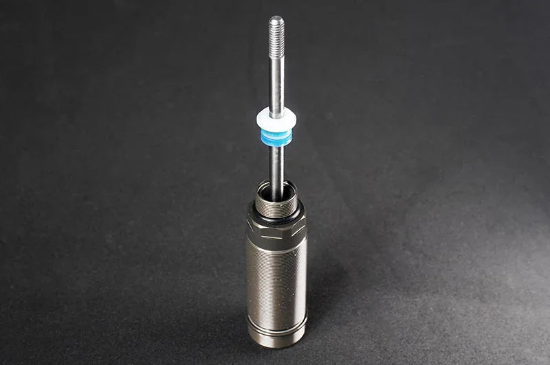 RC shock absorber body with threaded piston rod and seals on black background