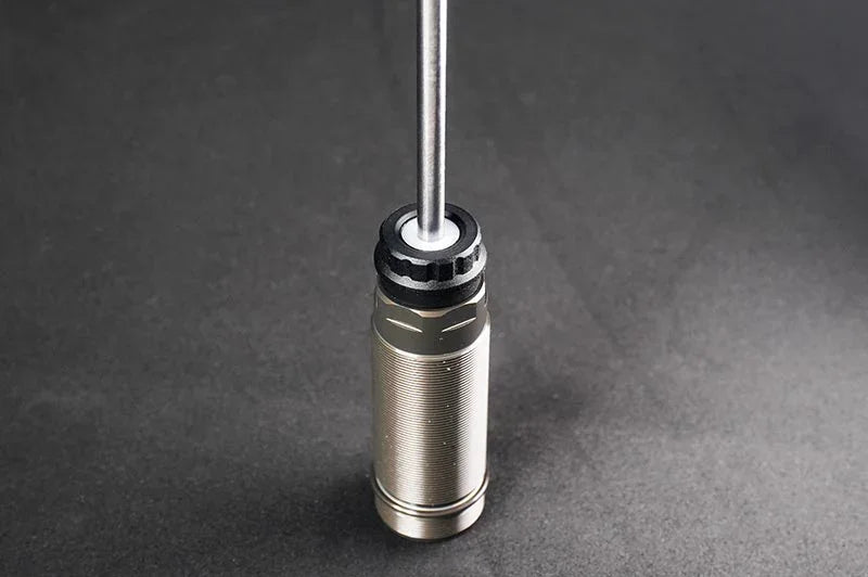Threaded metal RC shock absorber with rod on dark background, hobby parts detail