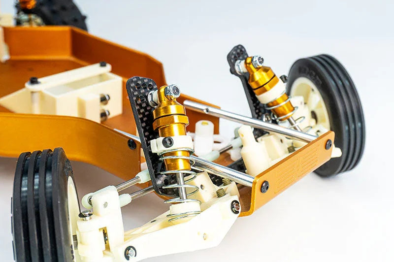 Close-up of RC car front suspension with dual shocks, gold alloy parts, and durable tires