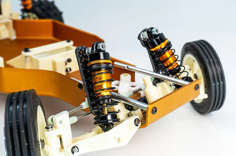 Close-up of RC car chassis with orange shock absorbers and front wheels, white background
