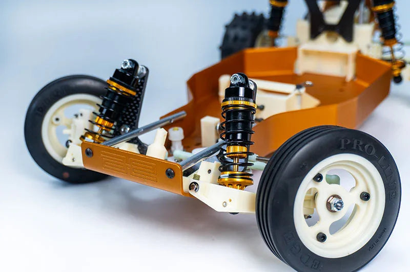 Close-up of RC car chassis with dual front shocks, Pro-Line tires, and visible suspension arms
