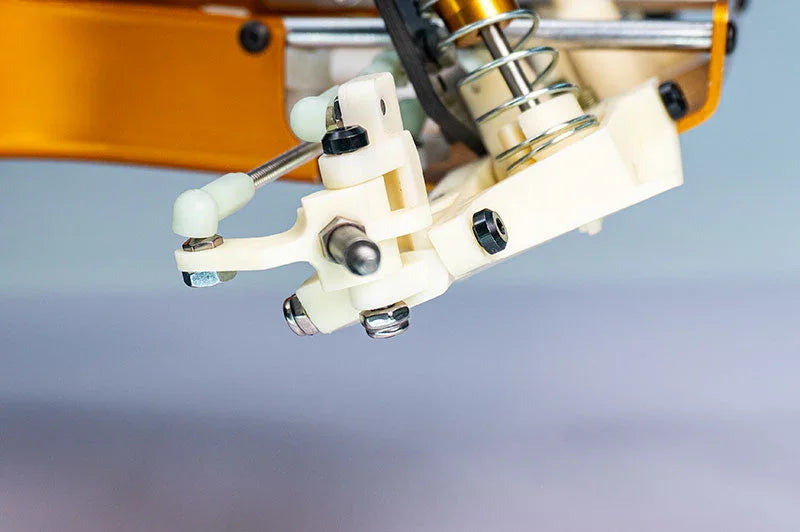 Close-up of RC car suspension assembly with white plastic parts, metal bolts, and shock absorber