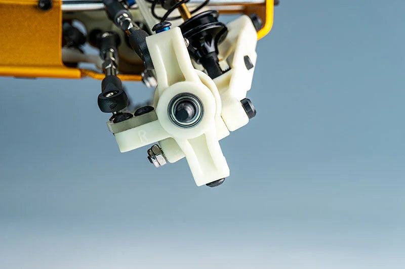 Close-up of a white RC car suspension hub with visible bearings and metal linkage arms