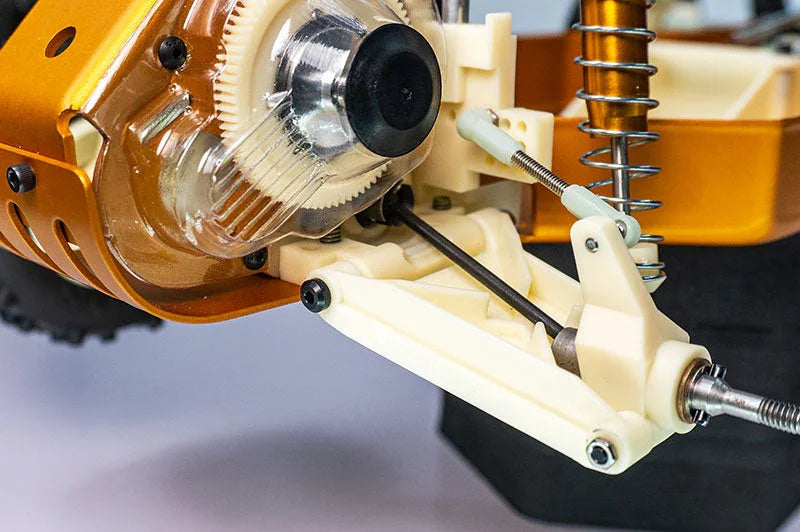 Close-up of RC car suspension arm, gears, and shock absorber with metal and plastic parts