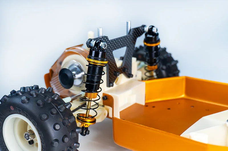 Close-up of RC car chassis with shock absorbers, off-road wheels, and carbon fiber parts