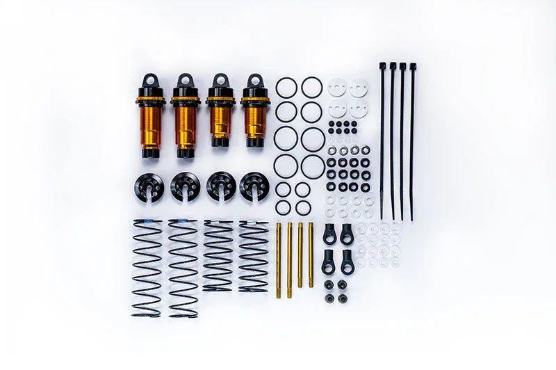 RC shock absorber kit with gold aluminum shocks, springs, O-rings, and accessories laid out on white background.