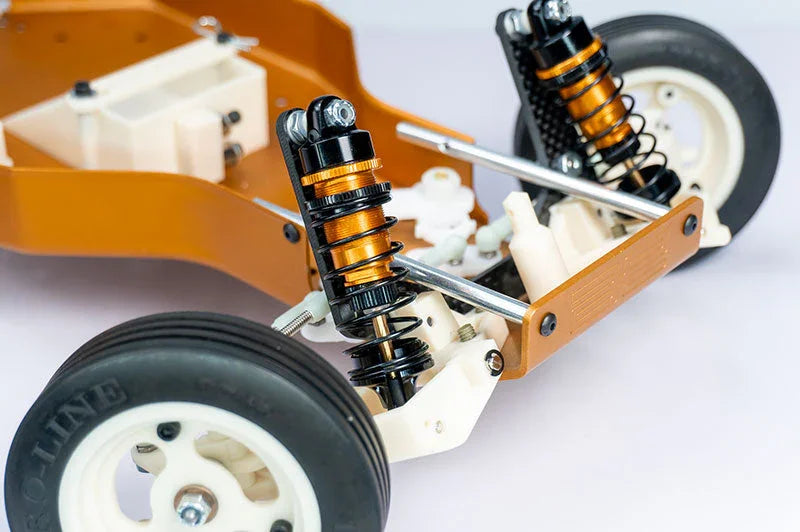 RC car chassis close-up with aluminum shocks, white wheels, and suspension arms