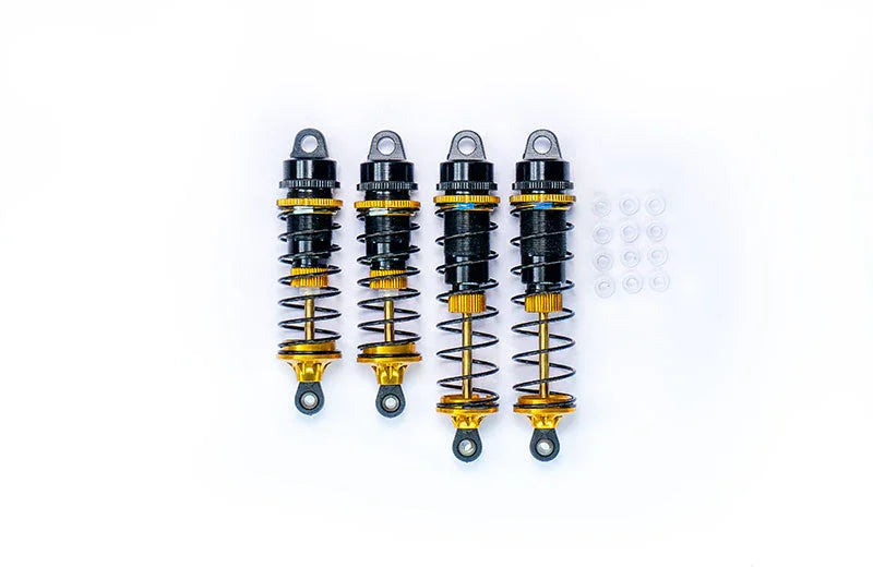 Set of four black and gold RC car shock absorbers with spare bushings on white background