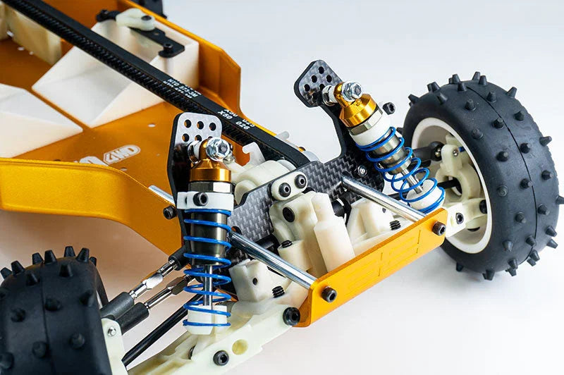 Close-up of RC car suspension system with coilover shocks, carbon fiber parts, and spiked tire.
