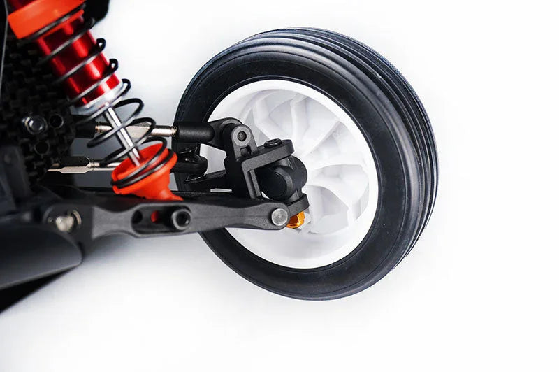 Close-up of RC car front wheel, shock absorber, and suspension on white background