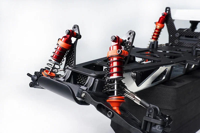 Close-up of RC car chassis with red aluminum shock absorbers and carbon fiber frame.