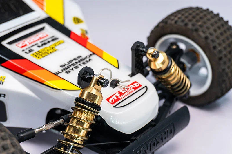 Close-up of RC car front suspension shocks with off-road tires and detailed decals.