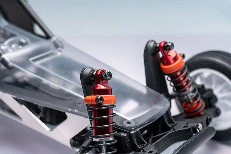 Close-up of RC car chassis with red aluminum shock absorbers and detailed suspension