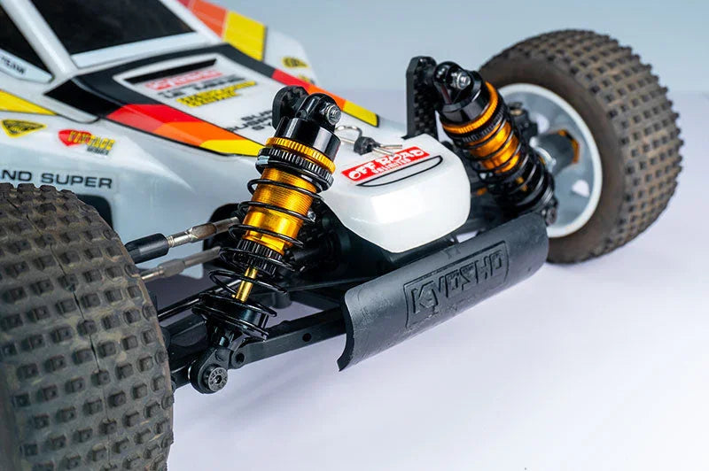 Close-up of RC car front suspension, off-road tires, and shock absorbers on white backdrop