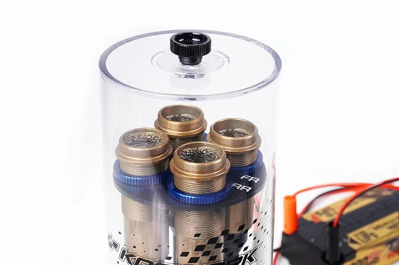 Clear vacuum chamber with four metal RC shock absorbers and visible battery wires