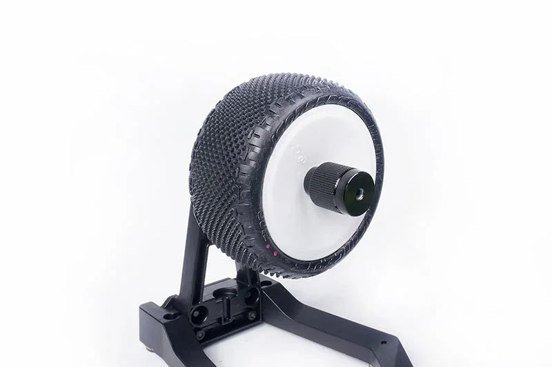 RC car tire balancing tool with mounted off-road tire on a black stand