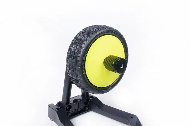 RC car wheel balancer with off-road tire mounted on black stand, isolated on white