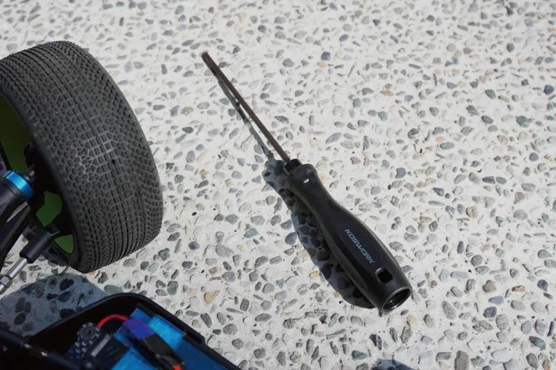 Koswork RC car tool with black handle beside buggy tire, outdoor surface, KOS13204 visible.