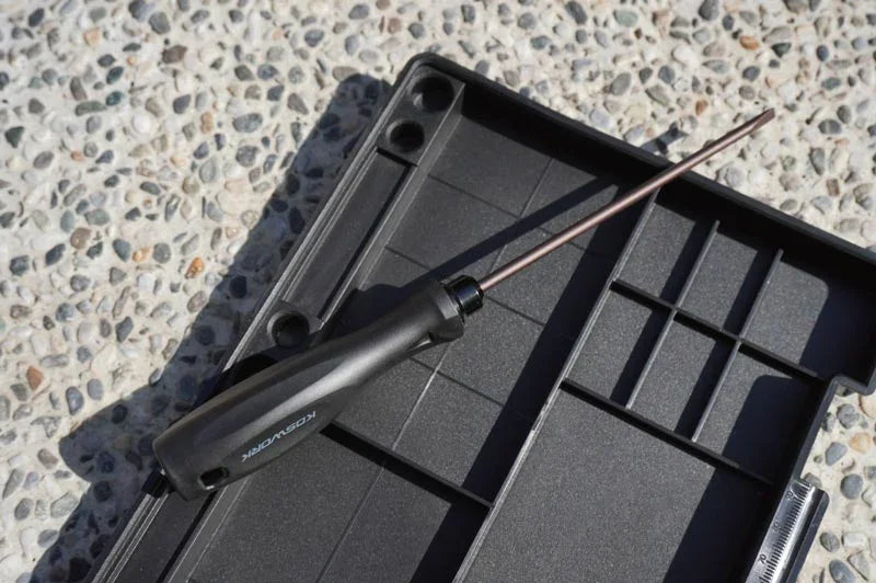 Koswork RC car tool, long metal shaft with black handle, on black accessory tray outdoors.