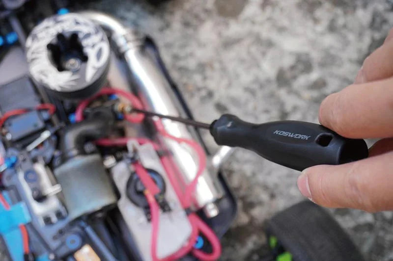 Koswork precision RC car tool with black handle adjusting RC vehicle component outdoors