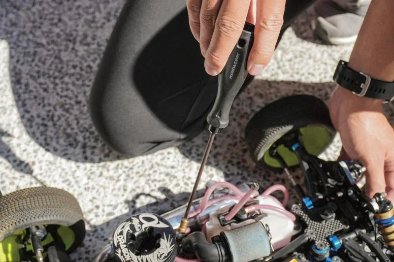 Koswork RC car tool in use, black ergonomic handle, tuning RC car engine outdoors