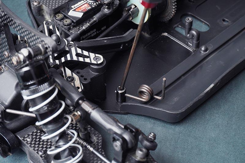 Koswork RC car accessory close-up showing suspension, metal tools, and black chassis detail