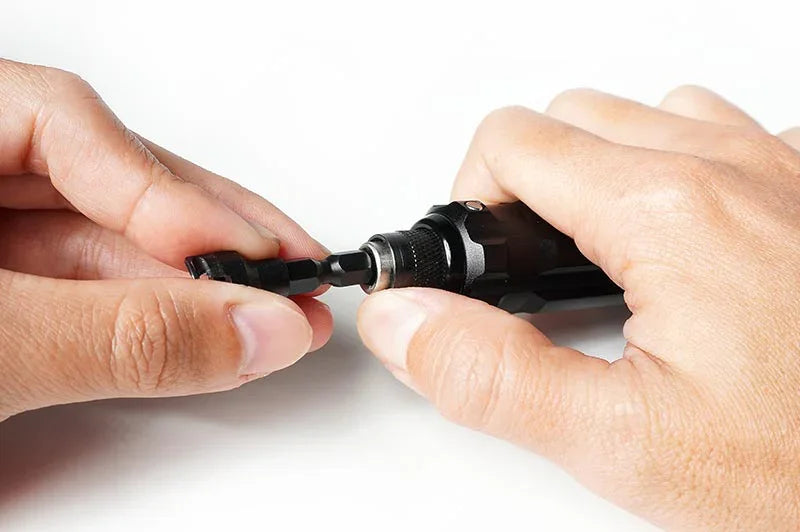 Close-up of hands using an RC hex driver tool with interchangeable bit on white surface