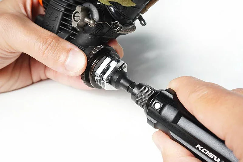 Hand using RC car tool to adjust engine part, showcasing hobby maintenance accessory