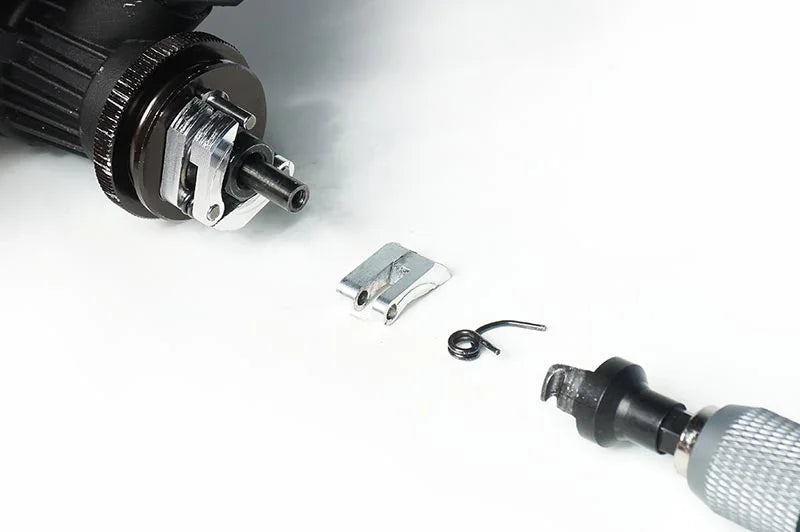 RC car clutch assembly with clutch shoes, spring, and tool on a white surface