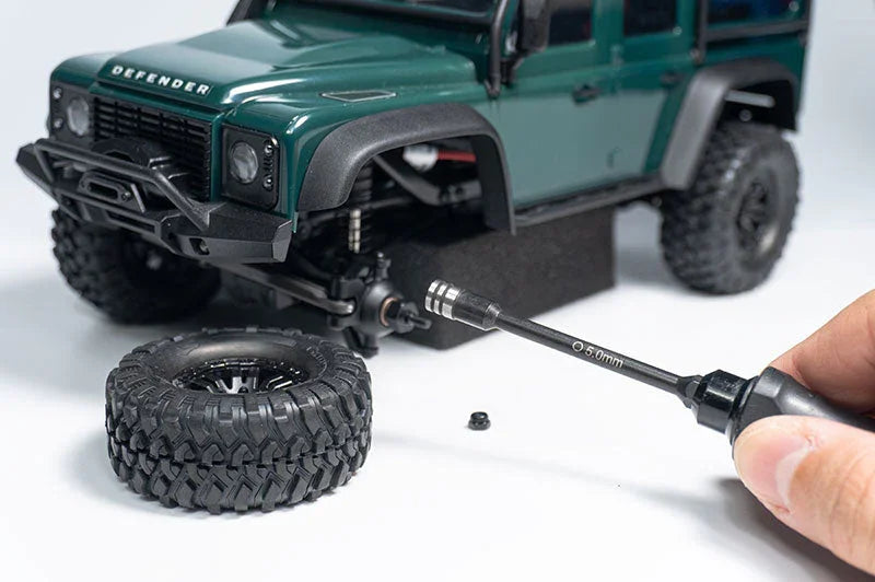 Koswork RC car 5.0mm hex driver tool unscrewing tire on green Defender model, accessory in use