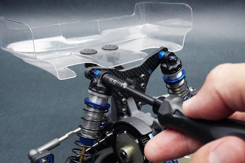 Koswork RC shock tool adjusting rear suspension of RC car with clear wing, tool marked 6.5mm