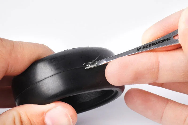 Koswork RC tire tool removing black rubber tire, close-up of tool marked KOSWORK