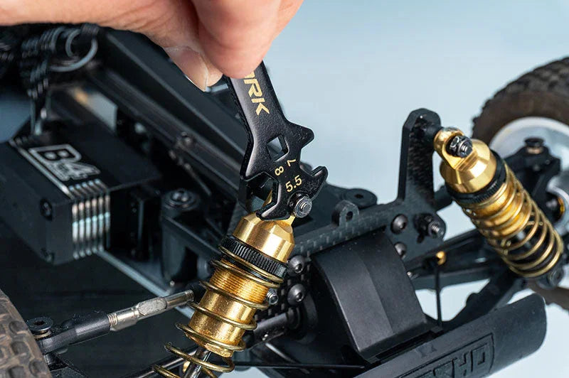 RC car shock absorber adjustment with hobby wrench tool, close-up, precision maintenance